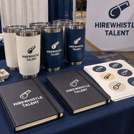 Custom swag notebooks and tumblers on a career fair booth table