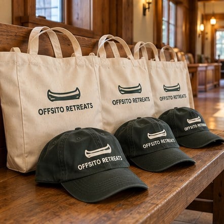 Custom branded totes and dad hats on a bench at an offsite lodge